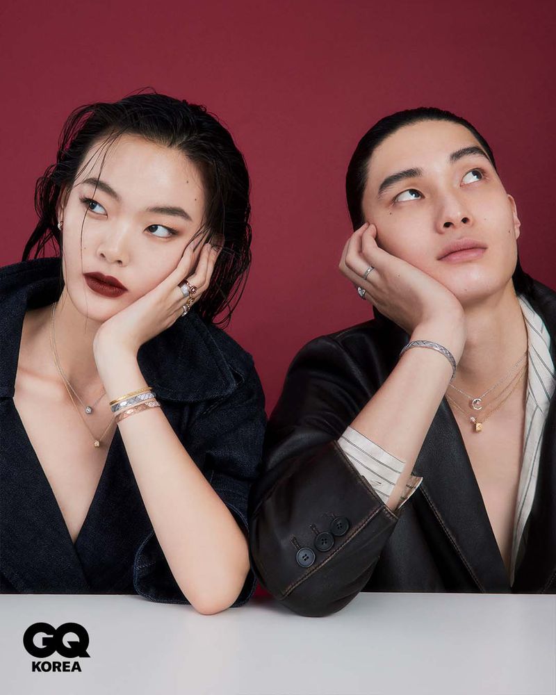 Two models leaning on their hands against a deep red backdrop for GQ Korea, wearing fine jewelry and dark clothing.