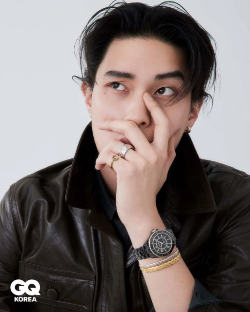 Close-up portrait of Jinyeong Pak wearing a brown leather jacket and watch, with hand near face against a white background for GQ Korea.