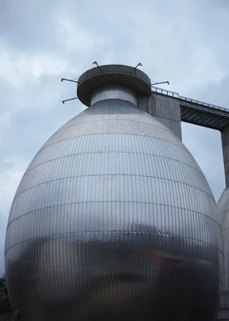 Large bulbous metallic industrial tank structure under an overcast sky with a connecting walkway