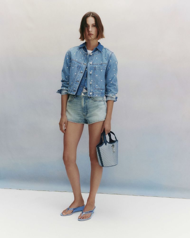 Model Mali Koopman in denim jacket and shorts holding a handbag for Veronica Beard April Trend Shoot