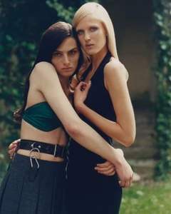 Vakare Steputyte and Lou Seriot embrace outdoors wearing a green crop top, pleated skirt, and black halter dress for Vogue Ukraine.