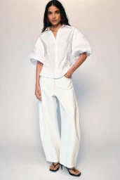 Model wearing a white puff-sleeve shirt and wide trousers against a white seamless background for Zara Vacation Mood