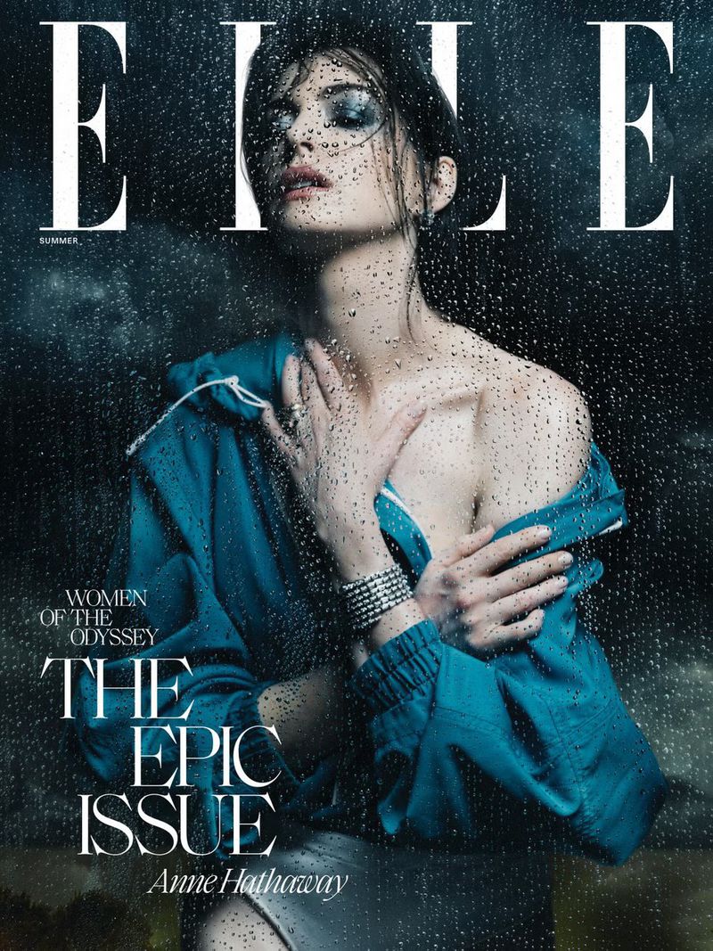 Elle magazine cover featuring Anne Hathaway, with rain-streaked glass effect. She wears a blue jacket and silver jewelry, set against a dark backdrop.