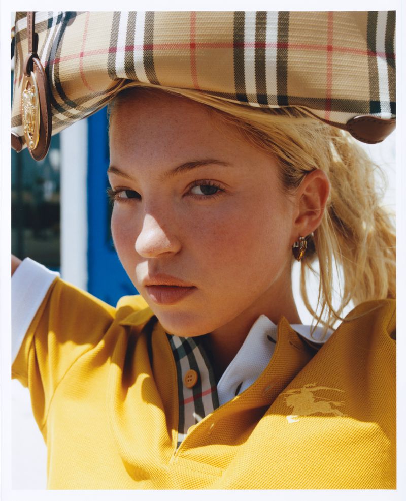 Model Lila Moss wearing a yellow polo shirt balances a plaid bag on her head for Who What Wear