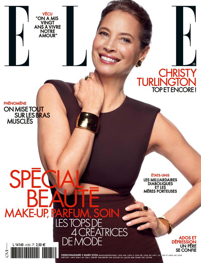 Christy Turlington poses on the cover of Elle magazine wearing a sleeveless brown dress with gold accessories and a bright smile.