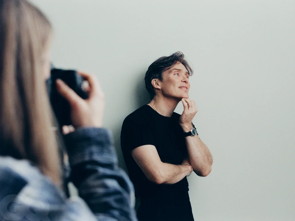 Cillian Murphy posing for a photoshoot with a photographer in the foreground holding a camera