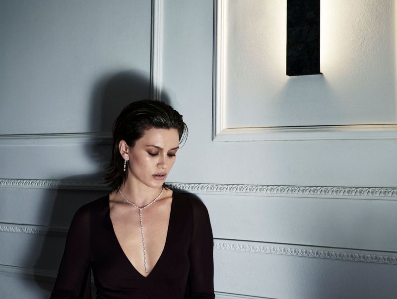 Model wearing a diamond lariat necklace and earrings against a white wall with wainscoting