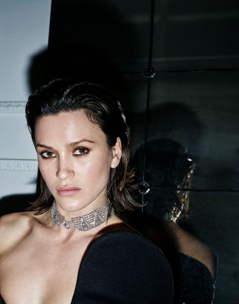 Model wearing a diamond choker necklace and dark clothing against a dark moody background