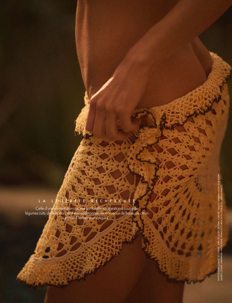 Woman wearing a crocheted sarong, showcasing fashion and textiles with warm lighting and blurred background, creating a soft, summery aesthetic.