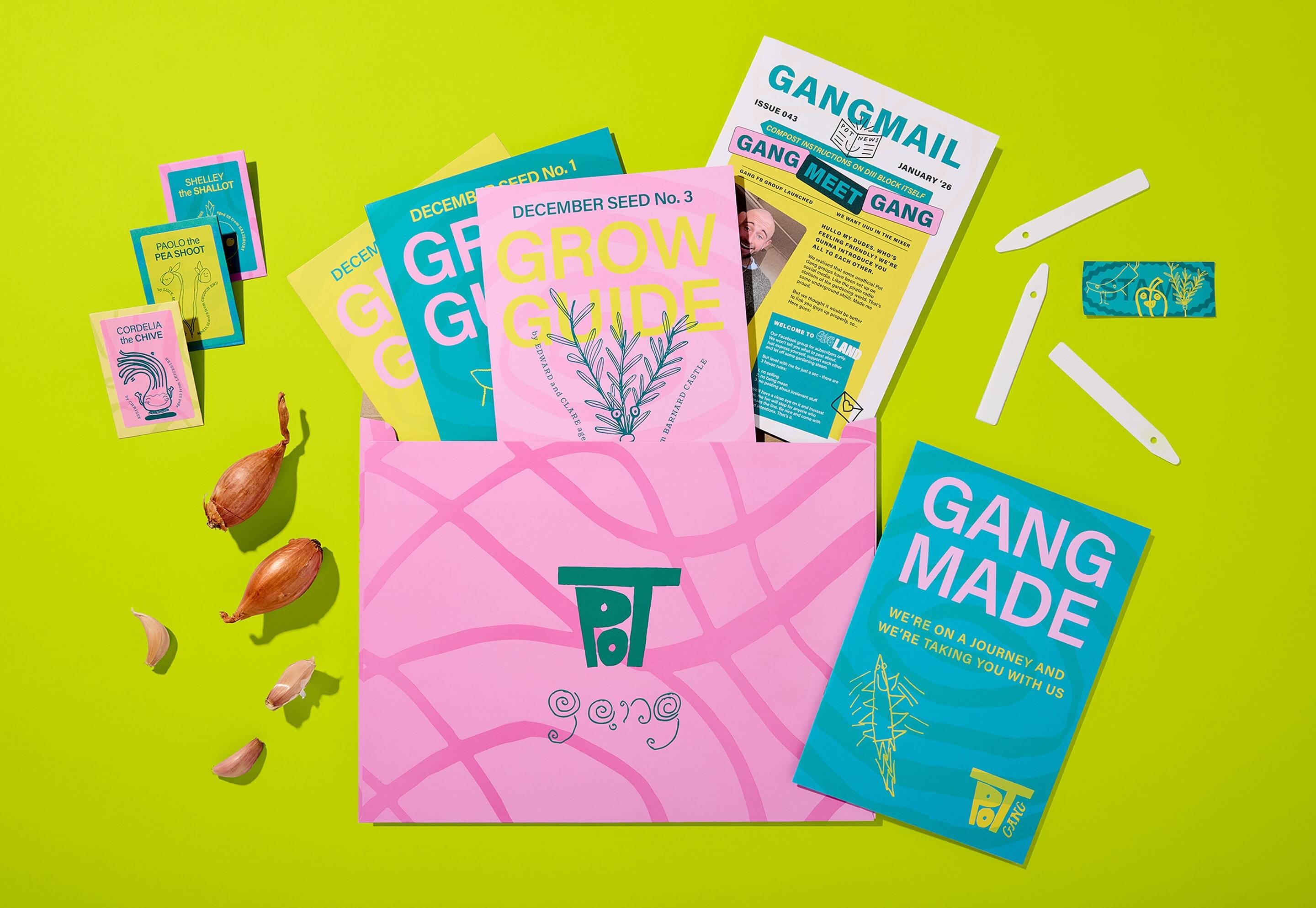 Flat lay of Pot Gang brand identity package with pink envelope, seed packets, grow guides, and fresh shallots on a vibrant green background.