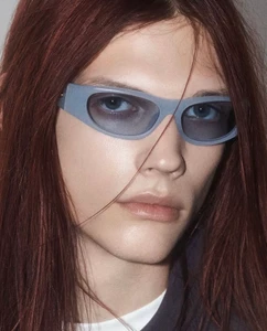 Close-up portrait of a model wearing light blue sunglasses with long reddish-brown hair for Casablanca Eyewear Collection