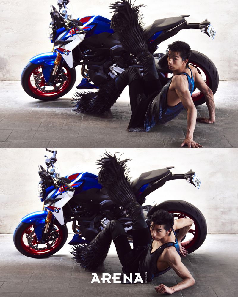 Model Yugo Takano in feathered boots posing on the ground next to a blue and white motorcycle for Arena Homme Plus Korea NEW ME project