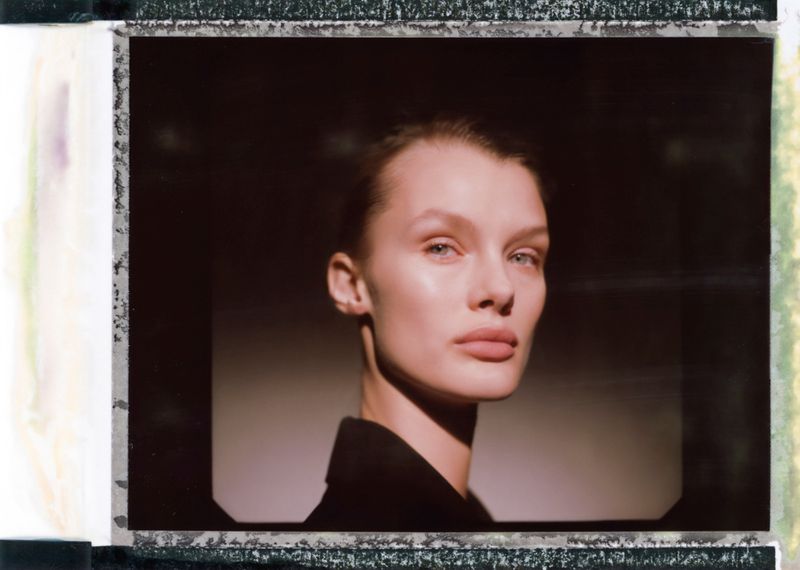 Portrait of model Kris Grikaite against a dark background in a polaroid frame format