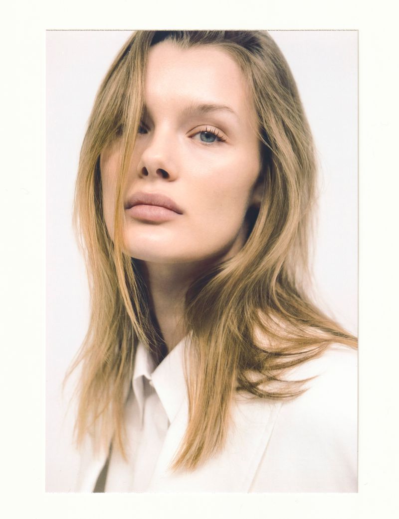 Close-up portrait of model Kris Grikaite wearing a white shirt against a clean white seamless background.