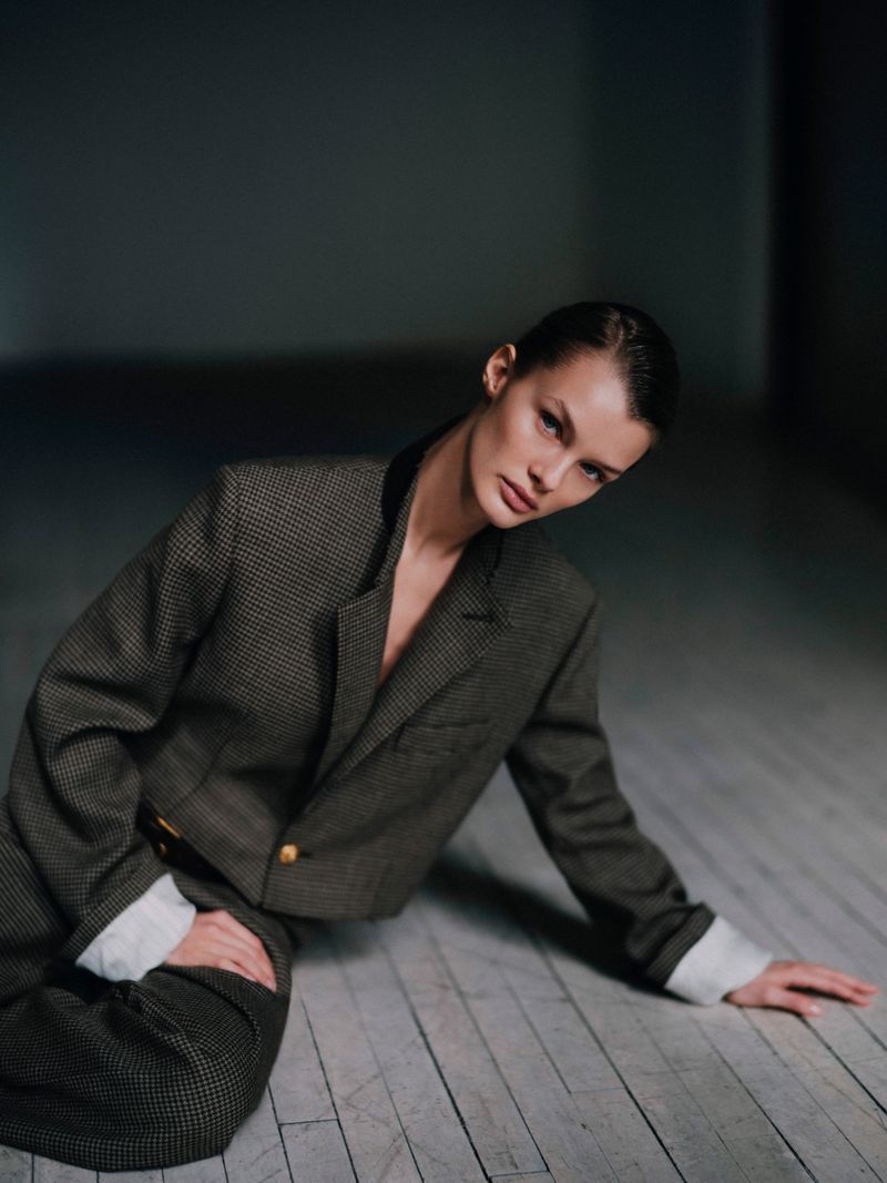 Kris Grikaite in a tailored patterned blazer seated on a wooden floor for DSECTION Magazine editorial photography by JuanKr.