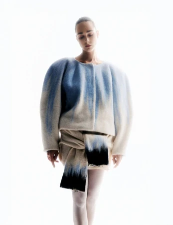 Model in sculpted cream and blue gradient jacket standing against a bright white background for Vogue Portugal.