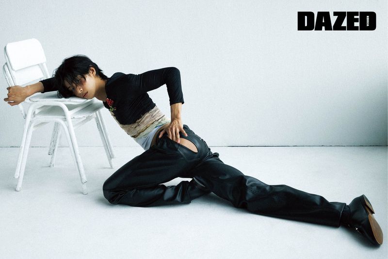 Model Yugo Takano in black top and leather trousers leaning on a white chair against a white background for Dazed & Confused Korea.