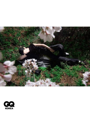 Model lying on grass among blooming white flowers in a fashion editorial for GQ Korea captured by Kim Hee June.