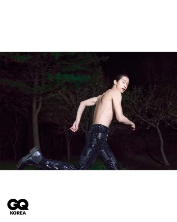 Shirtless male model wearing dark sequin trousers running outdoors at night for GQ Korea