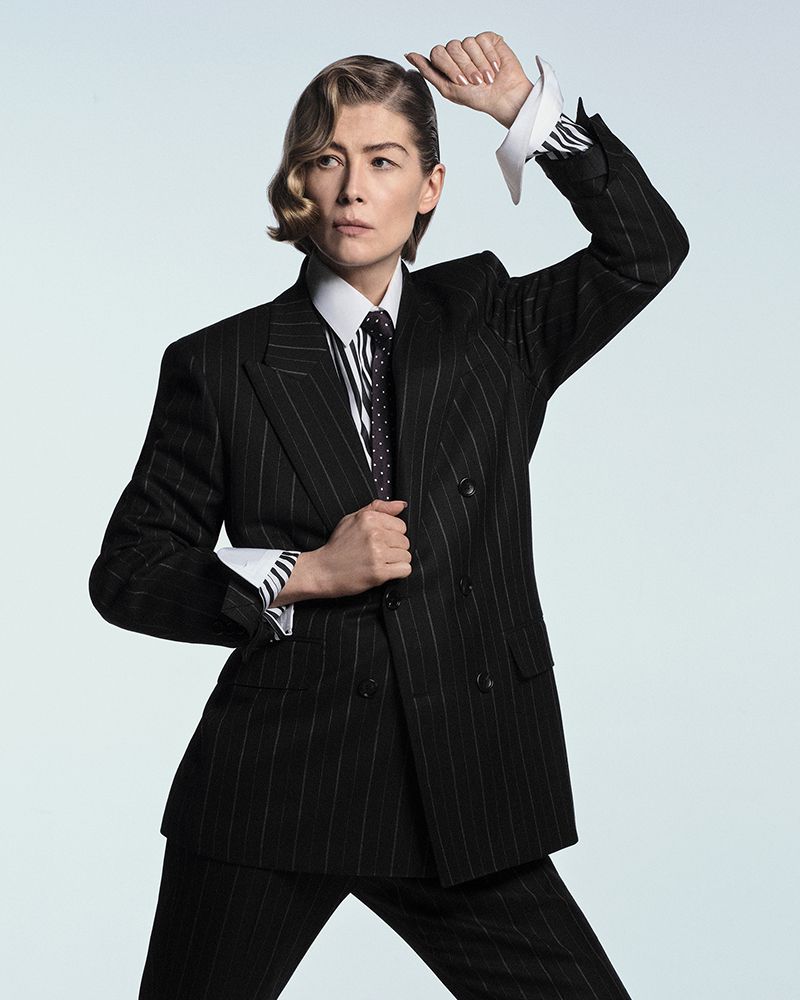 Rosamund Pike wearing a black pinstripe suit and tie against a plain light background for British GQ