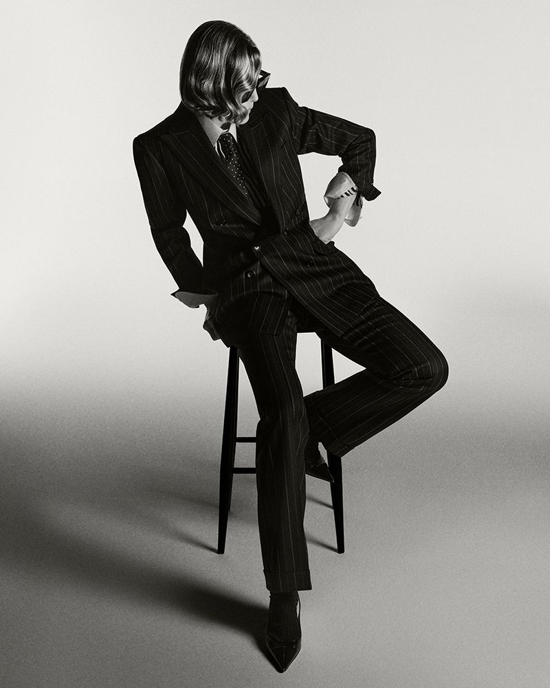 Rosamund Pike seated on a stool wearing a dark pinstripe suit and tie for British GQ