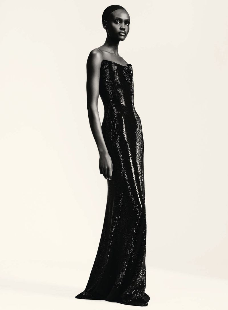 Model in a black strapless sequined evening gown against a plain light background