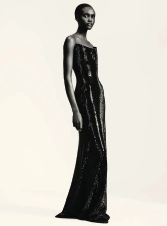 Model in a black strapless sequined evening gown against a plain light background