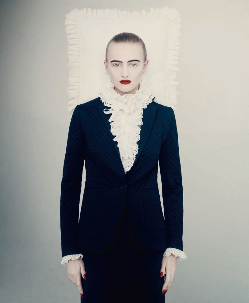 Model in a dark blazer with a ruffled white collar standing before a white backdrop for D Repubblica haute couture