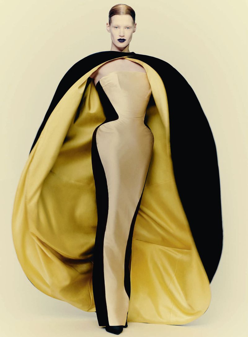 Model wearing a structured strapless gown with a voluminous black cape lined in gold for D Repubblica by Paolo Roversi.