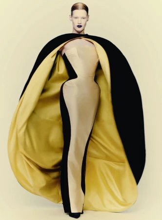 Model wearing a structured strapless gown with a voluminous black cape lined in gold for D Repubblica by Paolo Roversi.