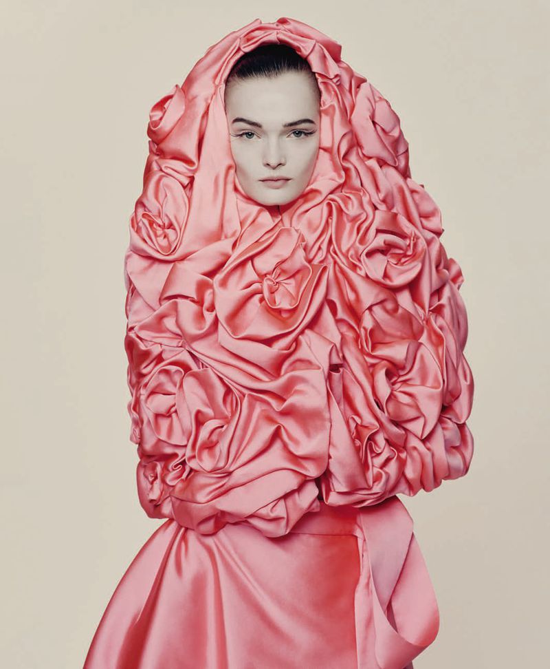 Model wearing a structured pink satin headpiece adorned with fabric rosettes for D Repubblica haute couture editorial