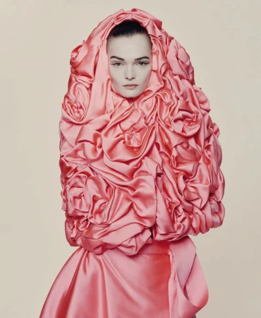 Model wearing a structured pink satin headpiece adorned with fabric rosettes for D Repubblica haute couture editorial