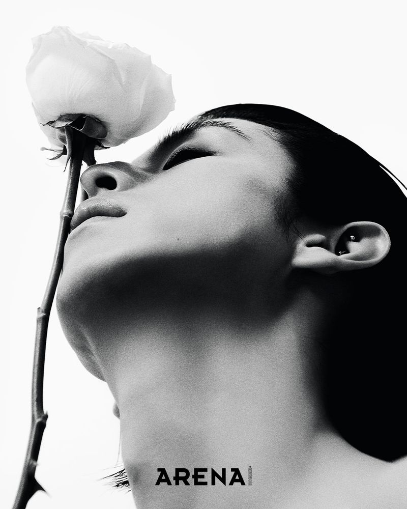 Black and white close-up profile portrait of a man tilting his head up toward a single white rose against a pure white background.