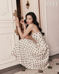 Model wearing polka dot dress crouching near an open white door wearing a wristwatch for Elle Korea editorial
