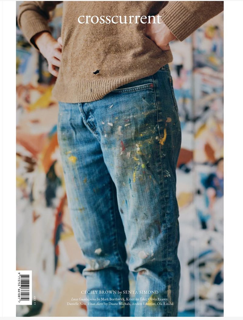 Cropped portrait of an artist in paint-splattered blue denim jeans and a brown knit sweater for Crosscurrent magazine.