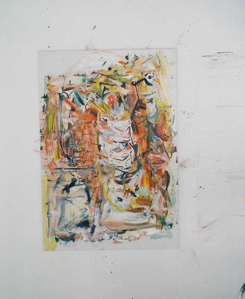 Abstract expressionist painting featuring dynamic multicolored brushstrokes on a vertical panel mounted on a white studio wall.