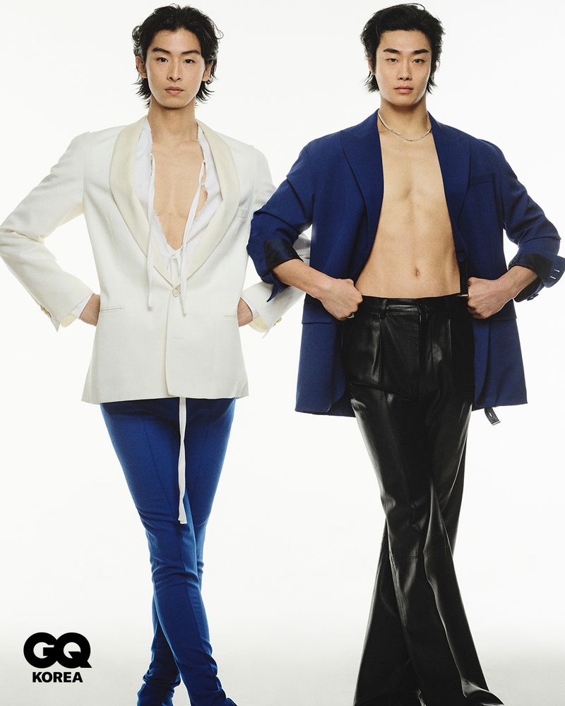 Two male models posing against a white background for GQ Korea wearing tailored blazers and trousers.