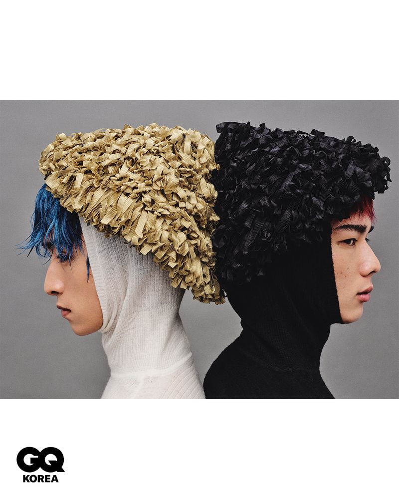Two male models back to back wearing textured hats and hoods against a grey background for GQ Korea editorial Power Puff