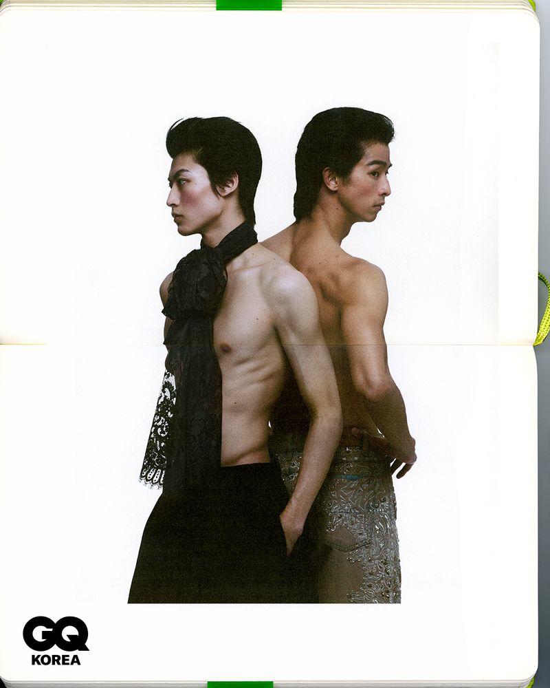 Two shirtless male models standing back-to-back against a plain white background for GQ Korea editorial.
