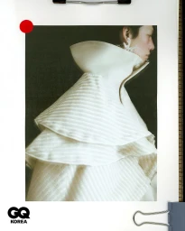 Model wearing a structured white high-collar ruffled garment in profile view against a plain background for GQ Korea.