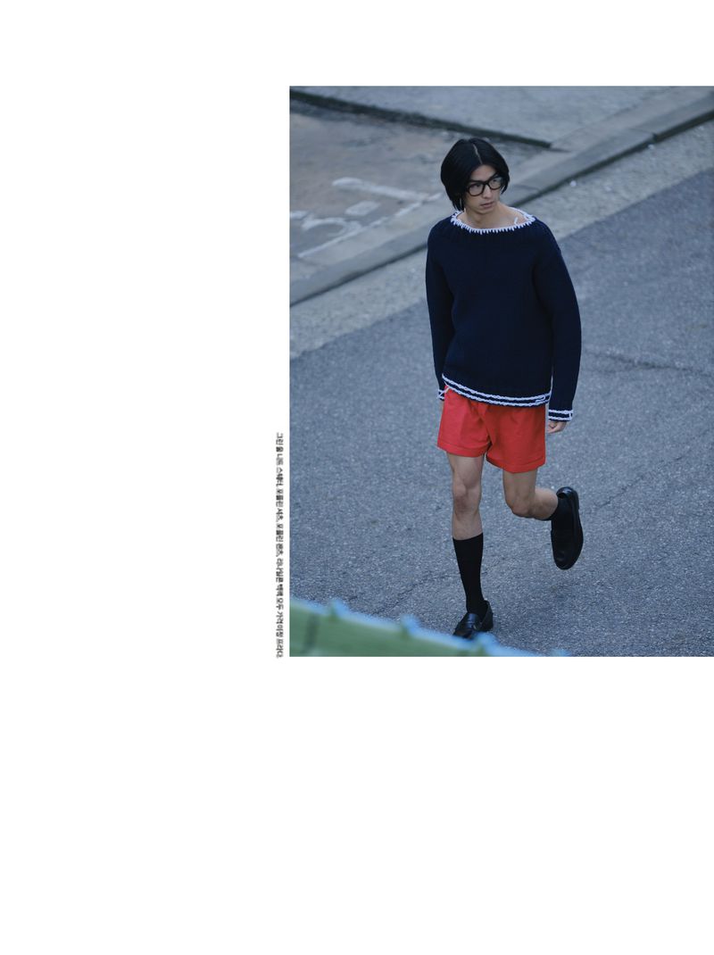 Model Yugo Takano in a navy knit sweater and red shorts walking outdoors on asphalt for Esquire Korea editorial.