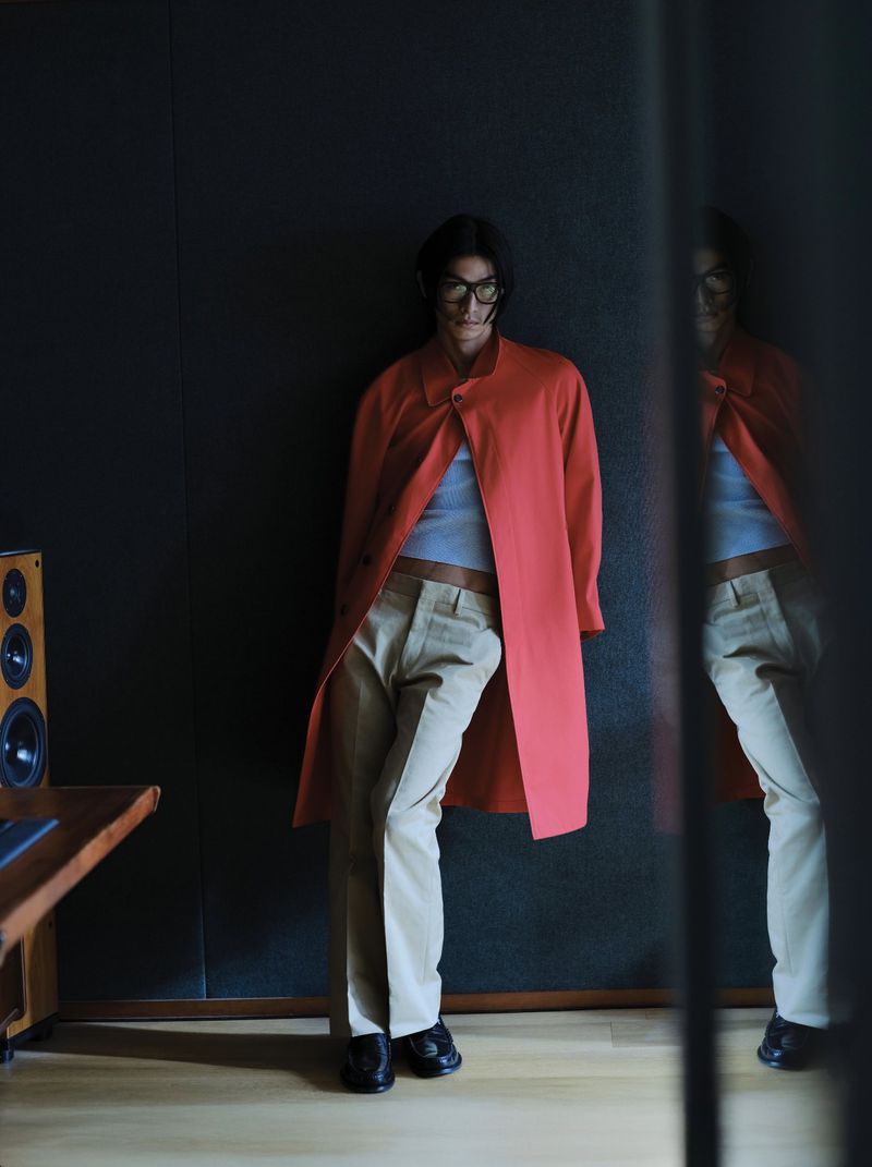 Model Yugo Takano in a red coat and tan trousers leaning against a dark wall for Esquire Korea