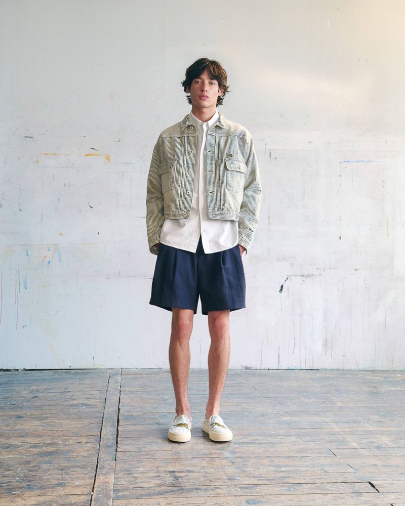 Model Max Fauviau wearing a cropped patterned jacket, white shirt, and navy shorts for KENZO Pre-Spring 2027.