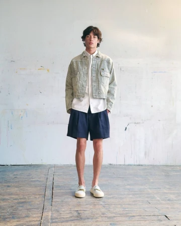 Model Max Fauviau wearing a cropped patterned jacket, white shirt, and navy shorts for KENZO Pre-Spring 2027.