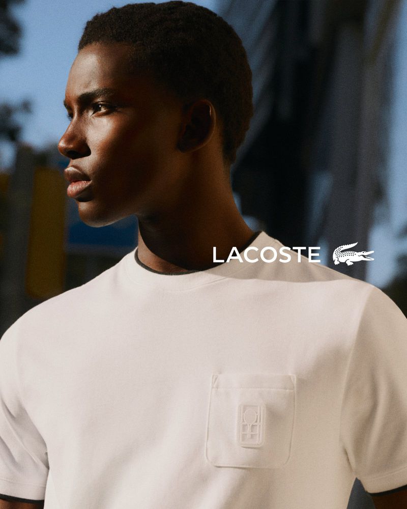 Close-up portrait of a Black man wearing a white t-shirt with a chest pocket against an outdoor backdrop