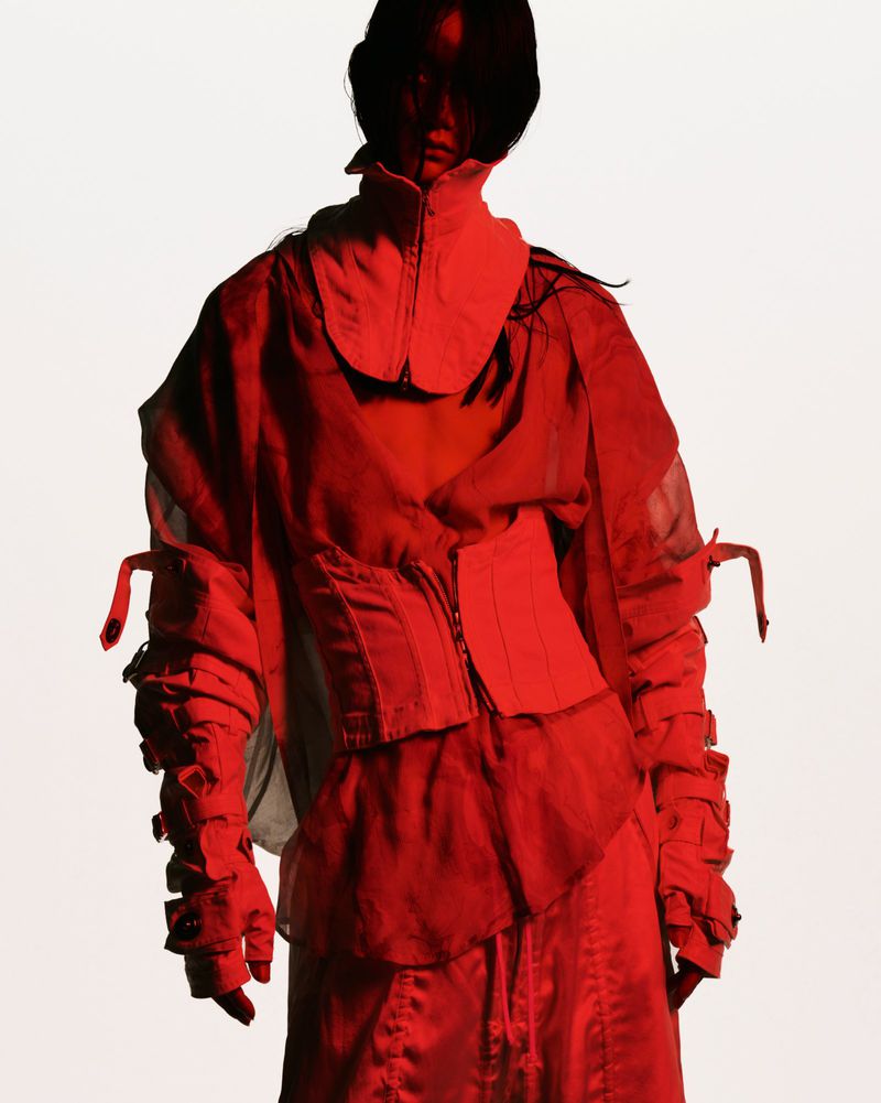 Model wearing avant-garde red layered clothing against a plain white background for Julius spring summer 2026