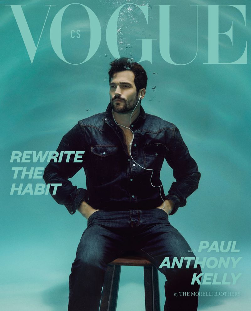 Paul Anthony Kelly submerged underwater wearing a dark denim shirt and jeans seated on a stool for Vogue CS.