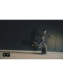 Model in motion wearing patterned garments running past dark paneling for GQ Korea