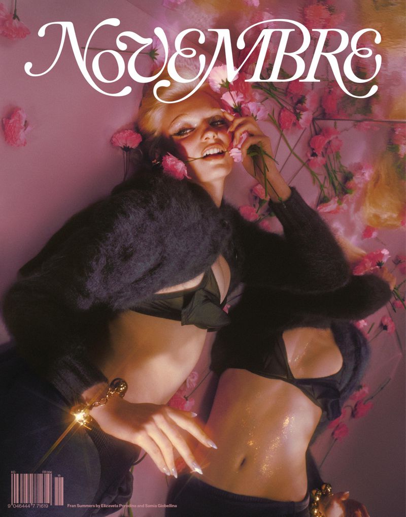 Fashion magazine cover featuring two blonde female models with dark tops posing against a pink backdrop with pink flowers.