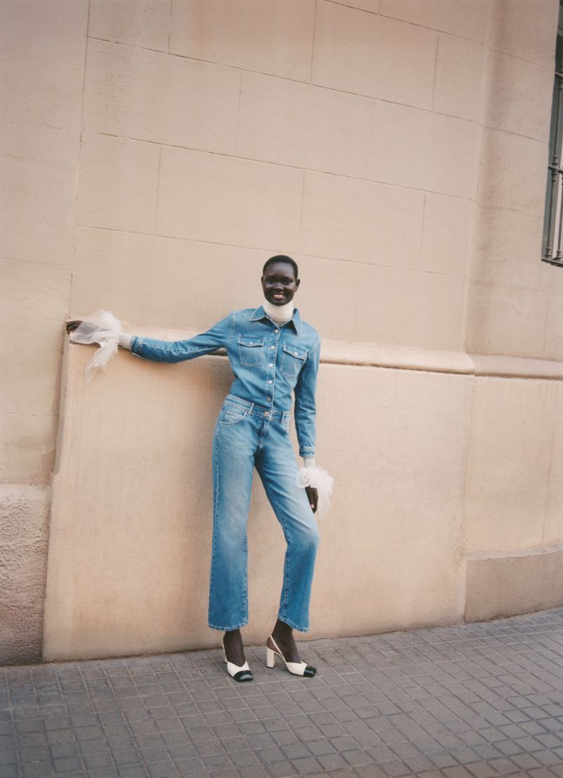Model wearing a blue denim shirt and jeans leaning against a plain wall for Vogue Polska